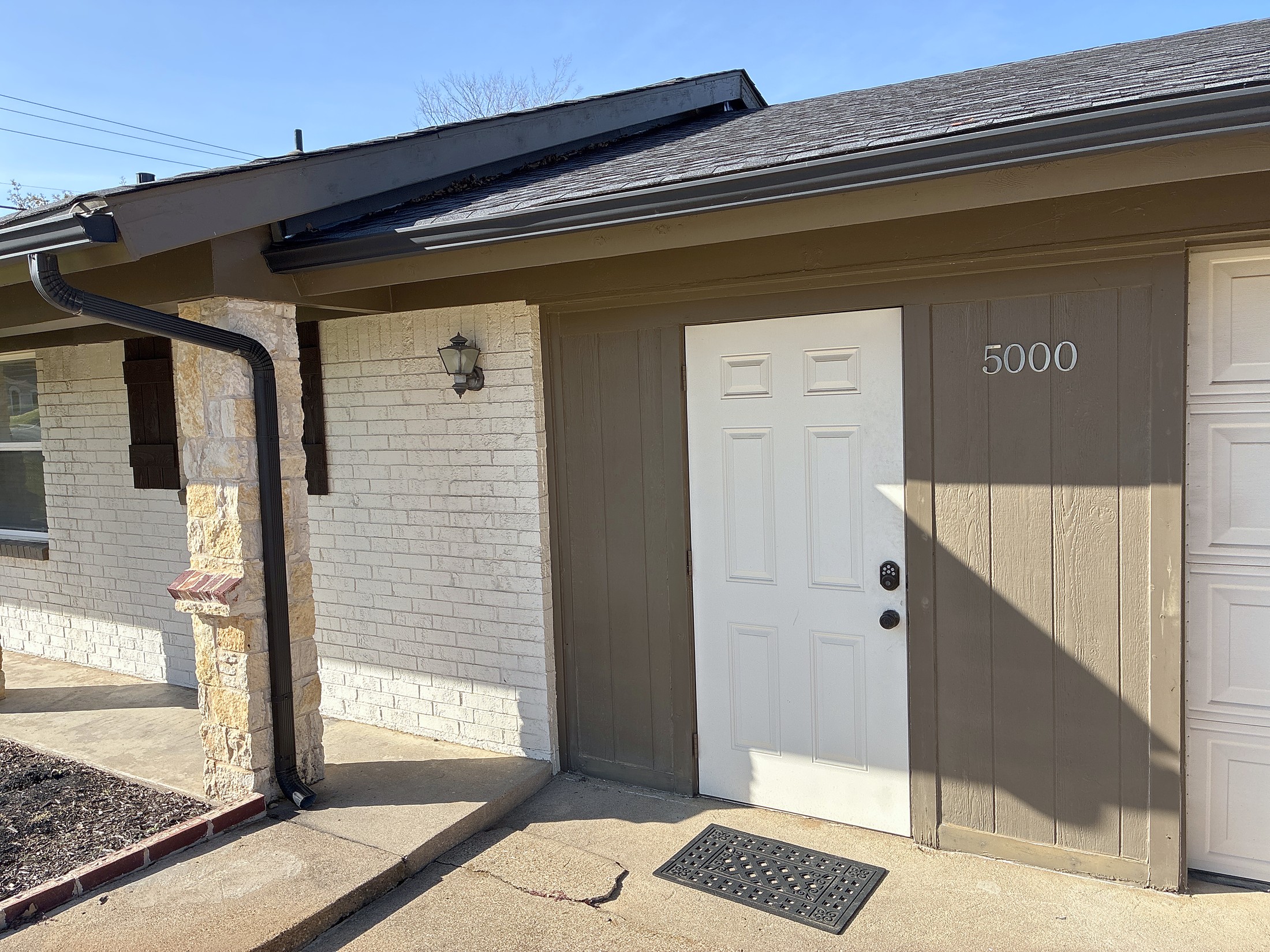 A single-story home entry with a new gutter and downspout