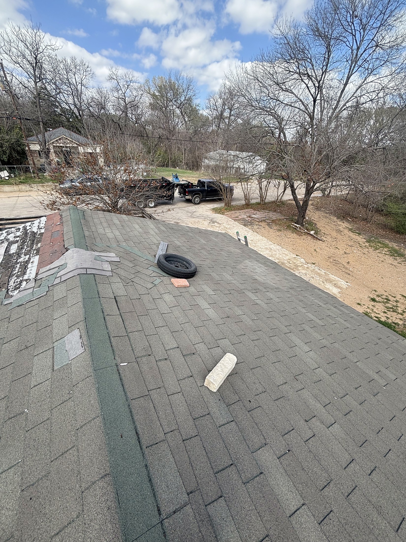A shingle roof and the street beyond it under a blue sky