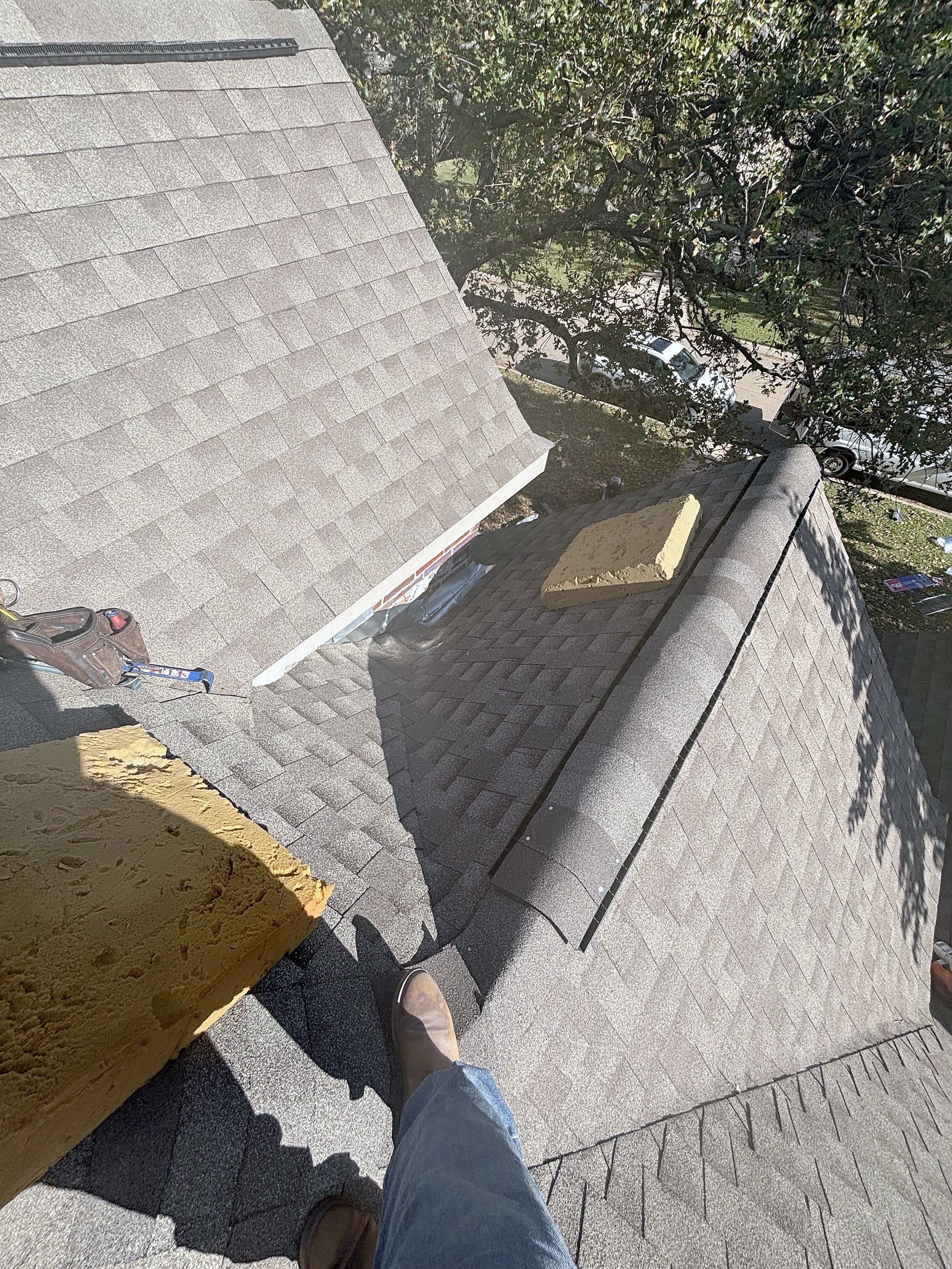 An old roof being torn off at a gable, with a shovel resting on the slope