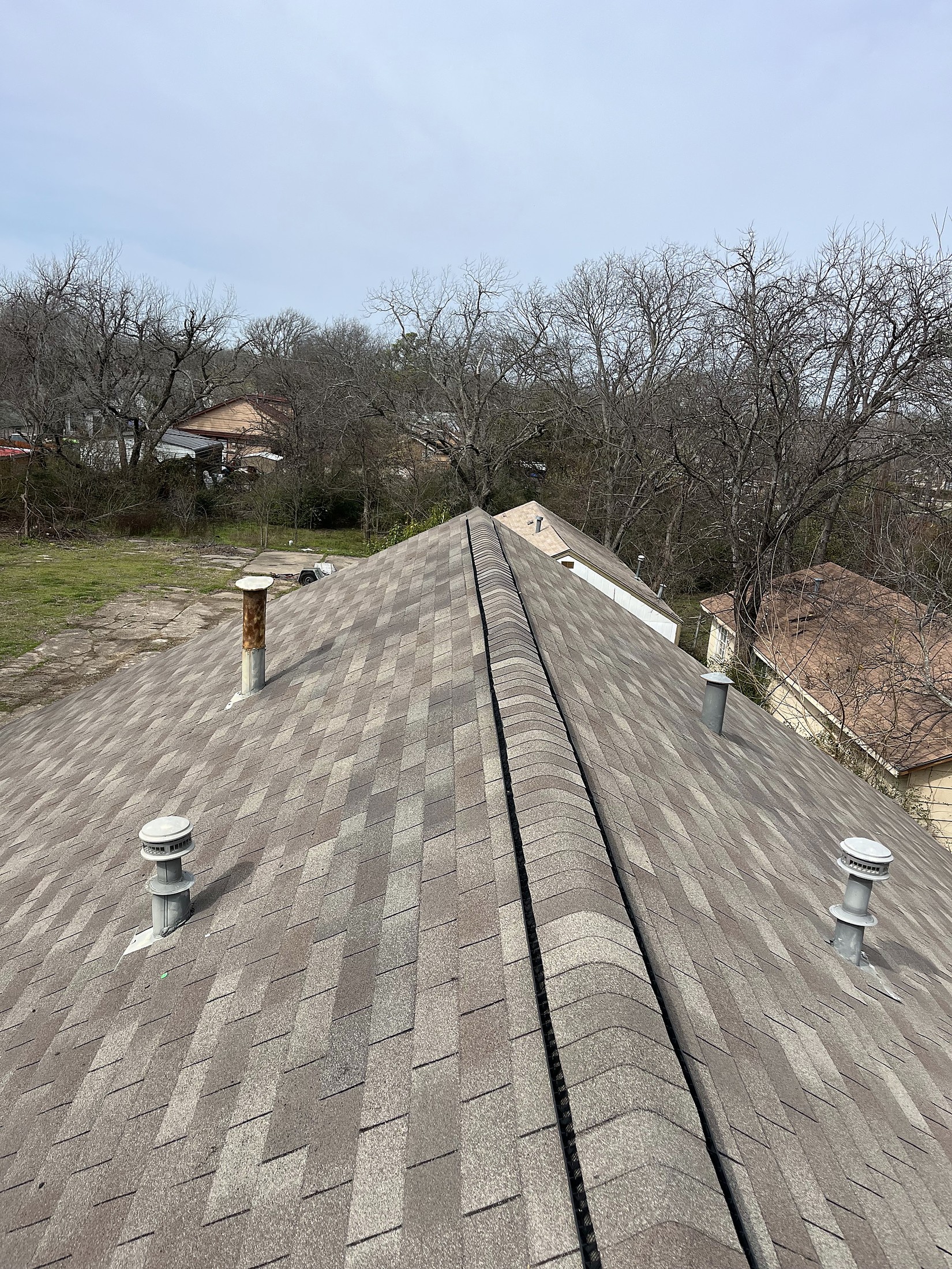 A finished ridge running across a shingle roof